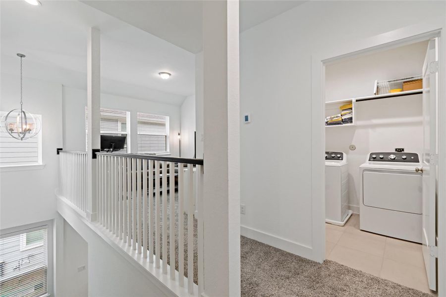 Bright upper-level hallway with plush carpeting leads to a convenient laundry room, featuring modern appliances and ample shelving. Bright upper-level hallway with plush carpeting leads to a convenient laundry room, featuring modern appliances and ample shelving.
