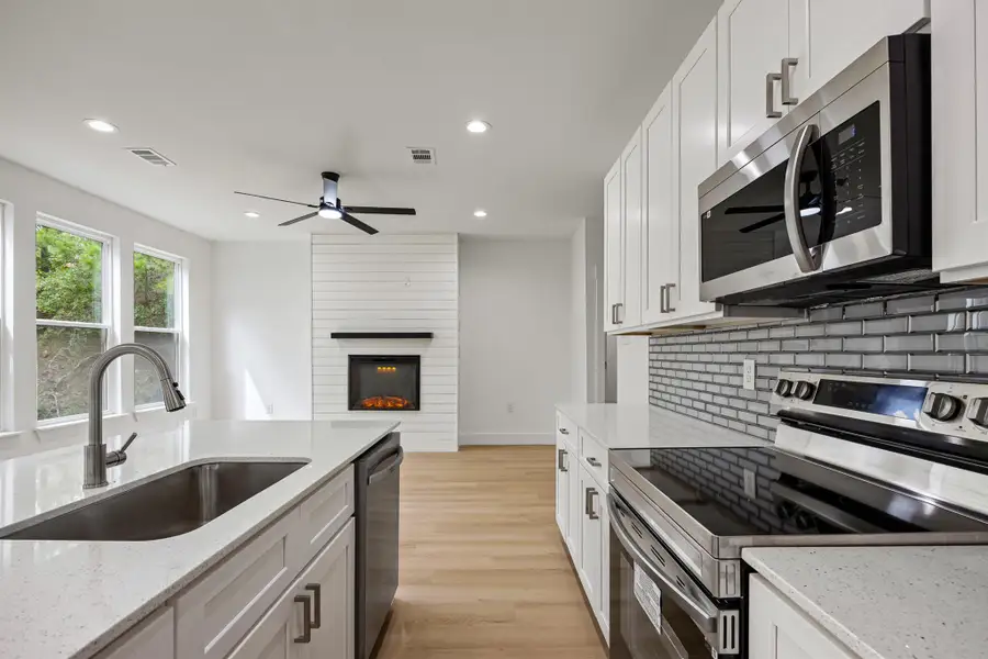 Kitchen featuring appliances with stainless steel finishes, decorative backsplash, a ceiling fan, recessed lighting, and light wood-style floors Kitchen featuring appliances with stainless steel finishes, decorative backsplash, a ceiling fan, recessed lighting, and light wood-style floors