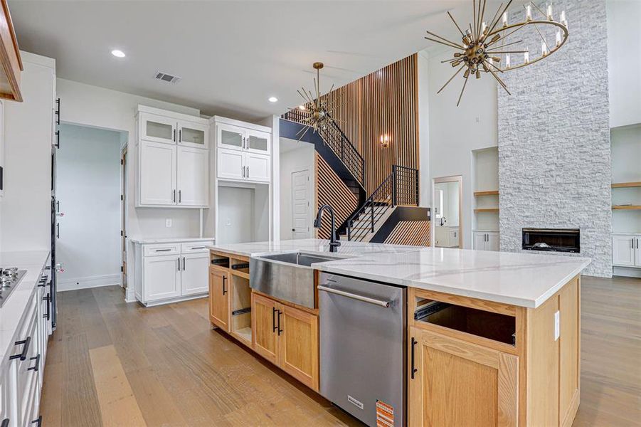 Kitchen featuring dishwasher, a chandelier, light wood-style floors, open floor plan, and glass insert cabinets