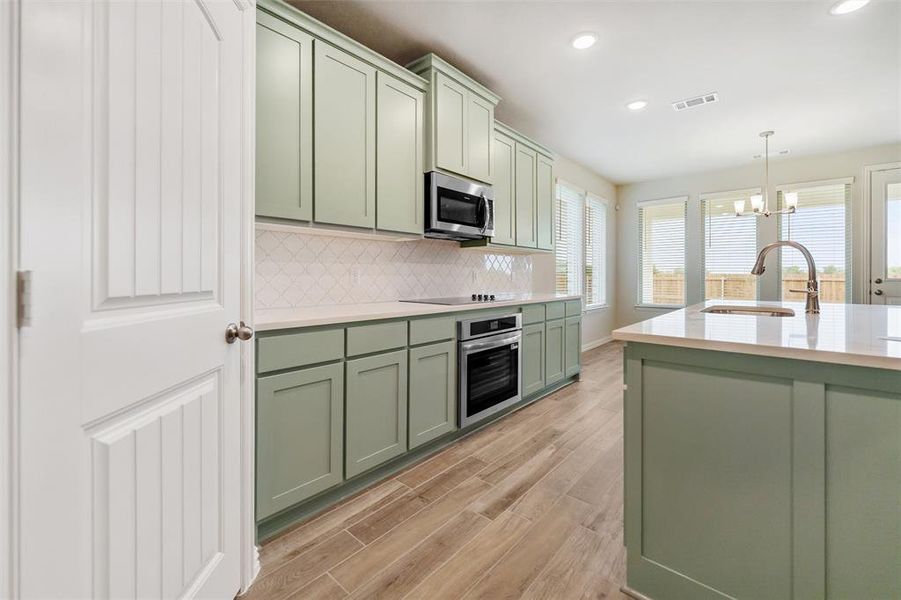 Kitchen featuring green cabinets, pendant lighting, appliances with stainless steel finishes, backsplash, and recessed lighting Kitchen featuring green cabinets, pendant lighting, appliances with stainless steel finishes, backsplash, and recessed lighting