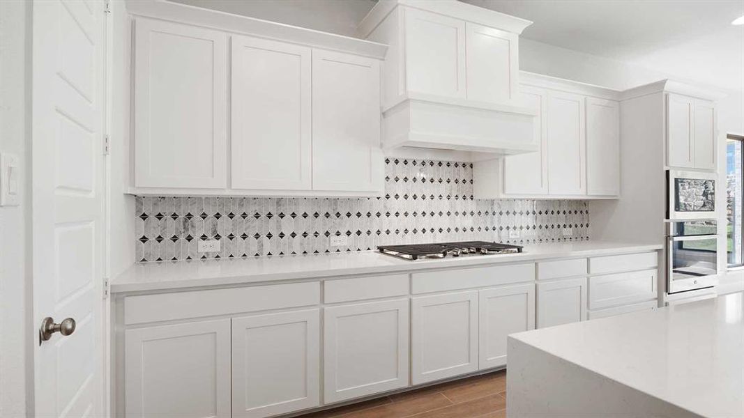 Kitchen with white cabinetry, appliances with stainless steel finishes, light wood-type flooring, and decorative backsplash