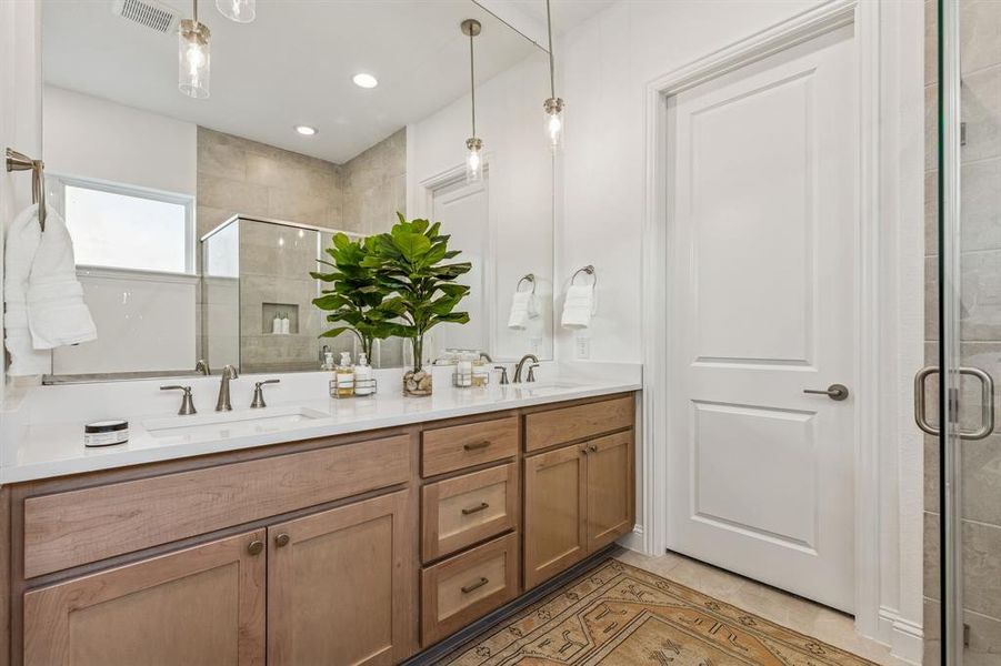 Full bath featuring double vanity, light tile patterned floors, a shower stall, and recessed lighting