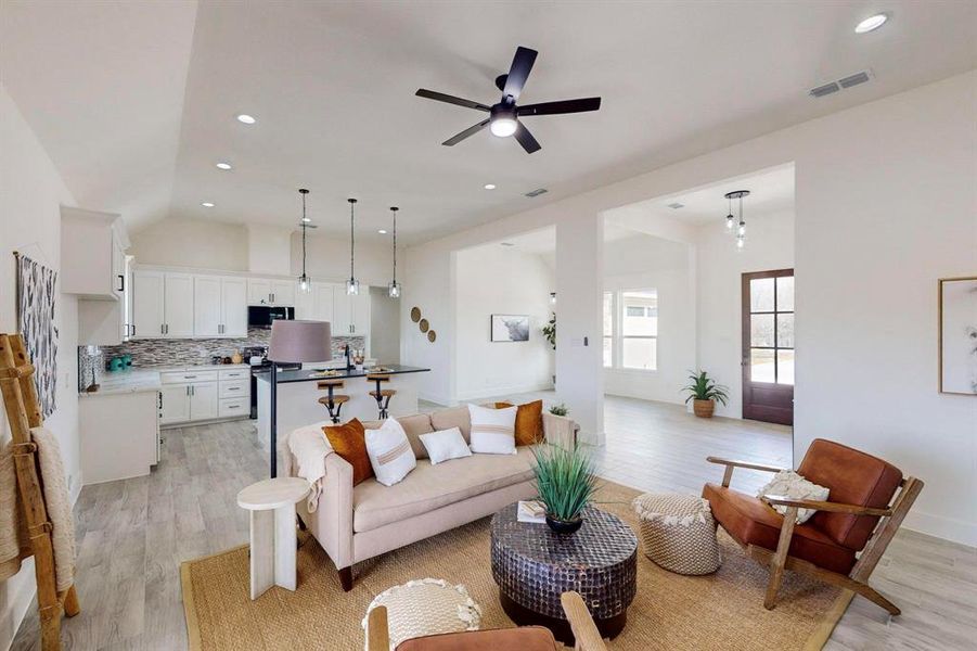 Living room with ceiling fan, light wood-type flooring, and vaulted ceiling