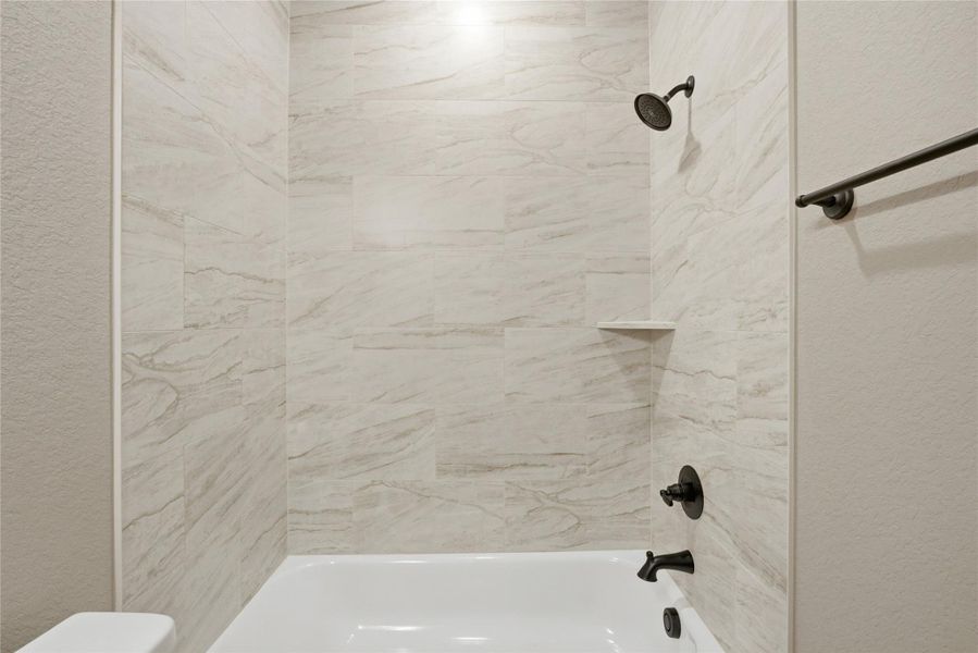 Full bath featuring a textured wall and  shower combination