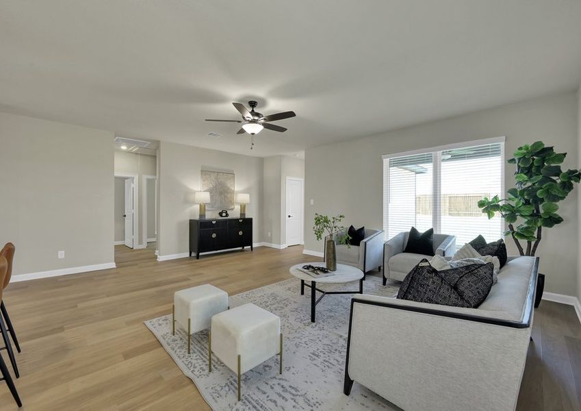Living room seating area featuring a sofa, a decorative credenza, greenery, and framed artwork.