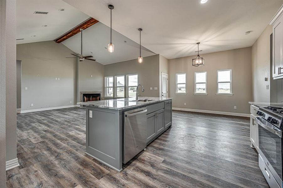 Kitchen featuring beam ceiling, a kitchen island with sink, stainless steel appliances, and dark hardwood / wood-style flooring