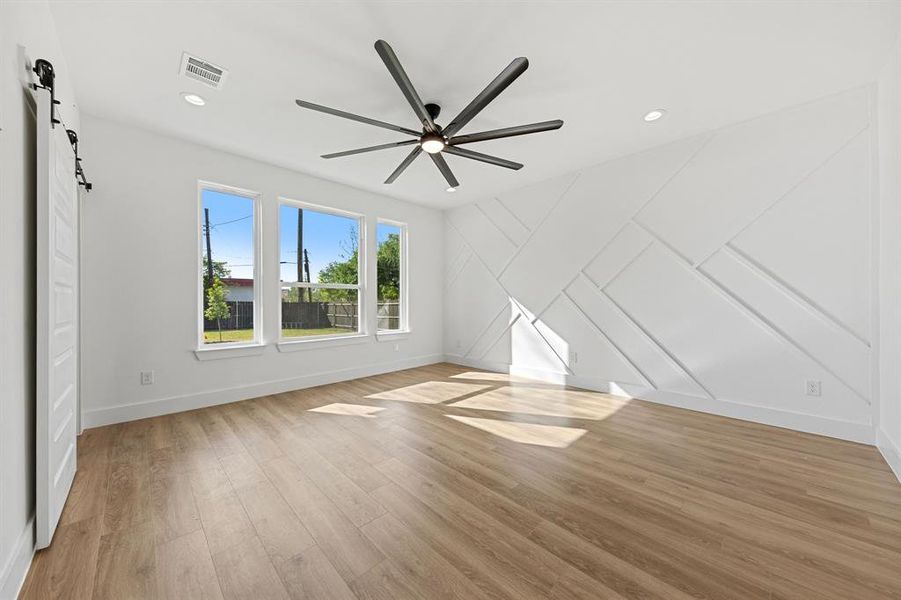This bright room features a decorative accent wall, recessed lighting, and a contemporary ceiling fan This bright room features a decorative accent wall, recessed lighting, and a contemporary ceiling fan