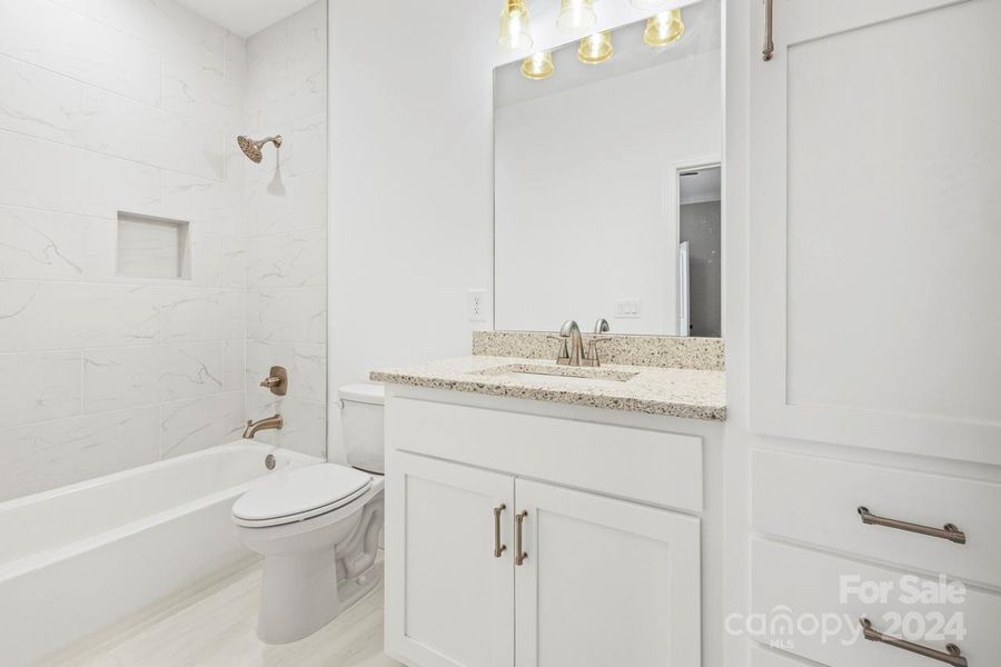 The full bathroom off of bedroom two features tile flooring, built in cabinets and tile shower/tub combo