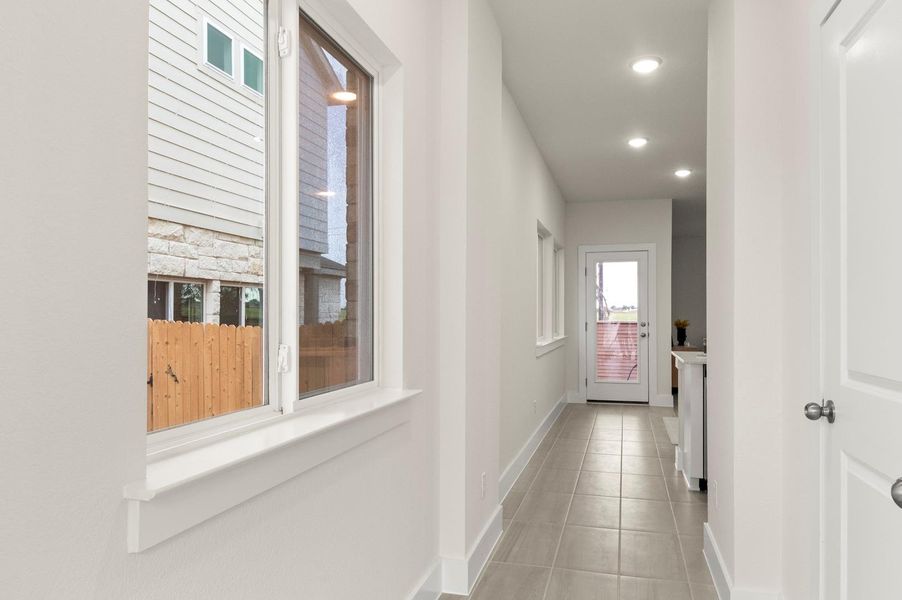 A well-lit hallway featuring sleek tile flooring and views of the surrounding neighborhood.