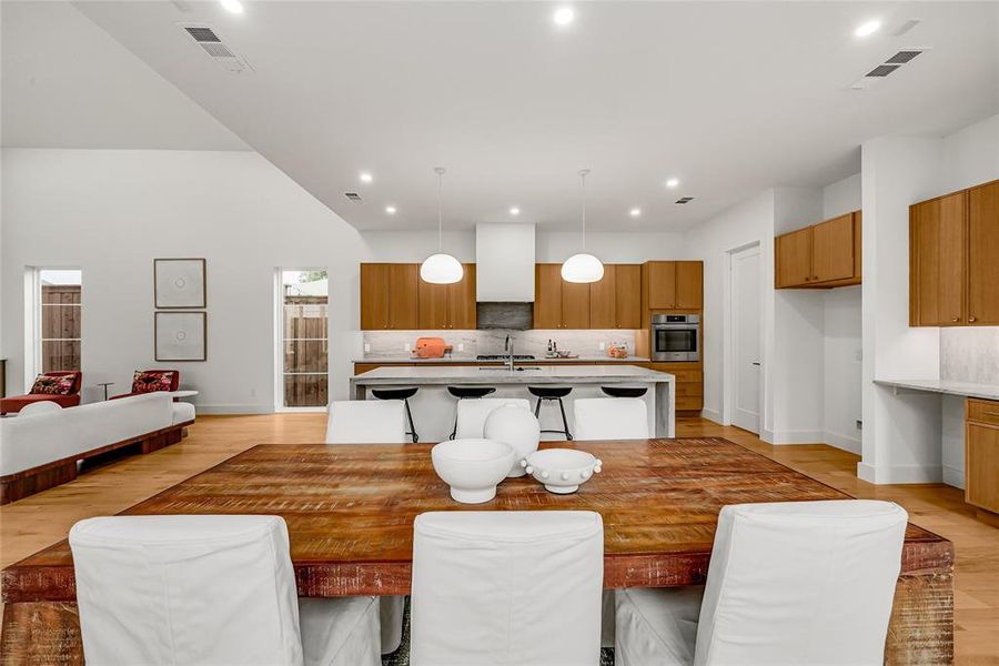 Open-concept interior featuring wood-finish flooring, a kitchen island with seating, a built-in oven, and recessed lighting