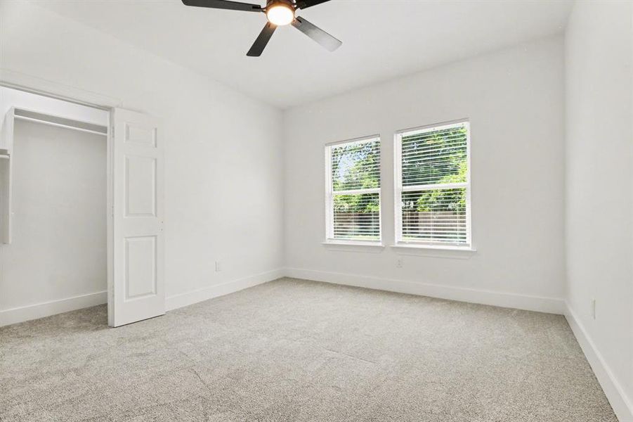 This room features neutral-toned carpet, white walls, and a ceiling fan