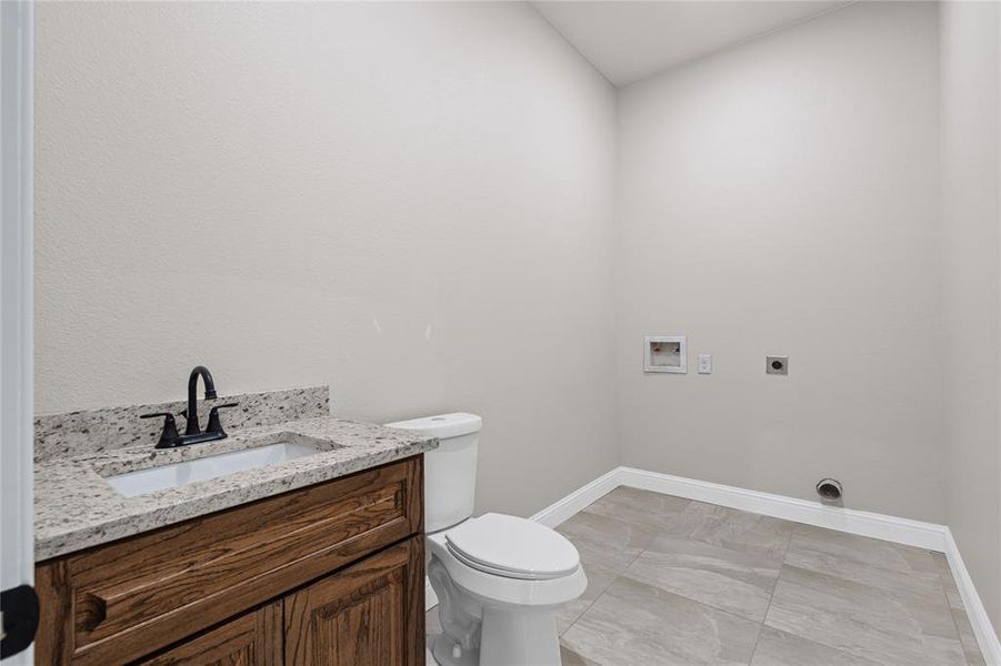 Half bath with toilet, baseboards, and vanity