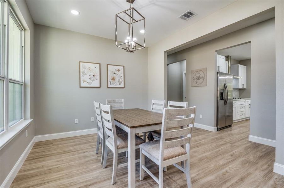 Dining room with light wood-style flooring, recessed lighting, and a chandelier