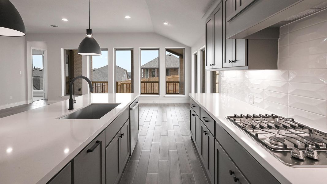 Kitchen with light countertops, a sink, tasteful backsplash, wood finish floors, and stainless steel appliances Kitchen with light countertops, a sink, tasteful backsplash, wood finish floors, and stainless steel appliances