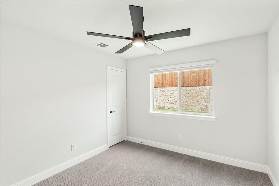 Empty bedroom with gray carpet, white walls, ceiling fan, and single window Empty bedroom with gray carpet, white walls, ceiling fan, and single window