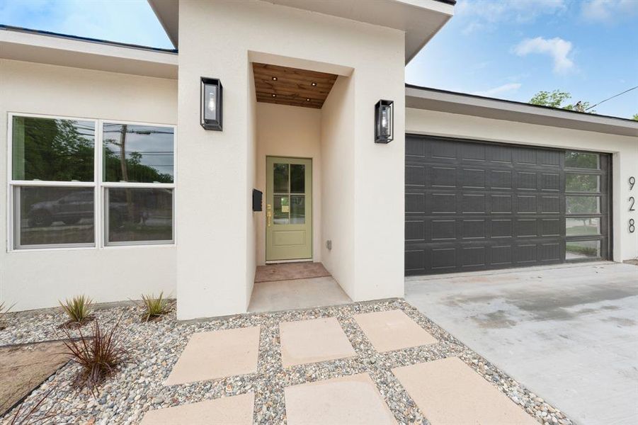 Entrance to property featuring a garage, stucco siding, and concrete driveway