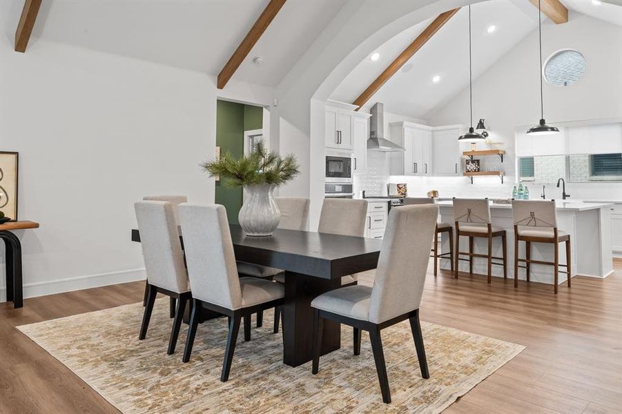 Dining space with high vaulted ceiling, beam ceiling, light wood finished floors, and recessed lighting
