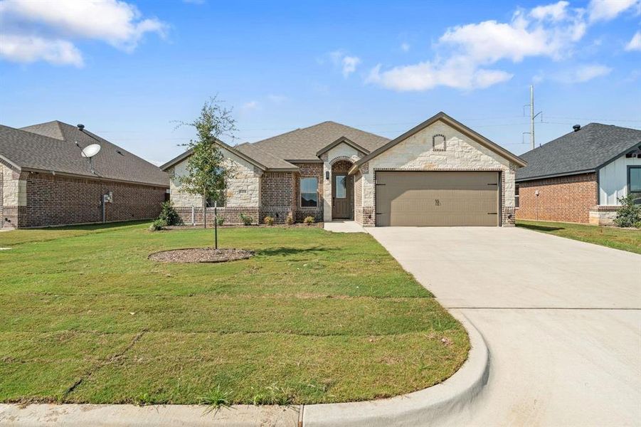 View of front of house featuring concrete driveway, a front yard, an attached garage, and brick siding