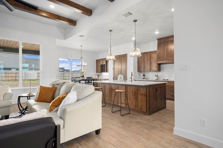 Living area with light wood-type flooring, beam ceiling, and hanging lights