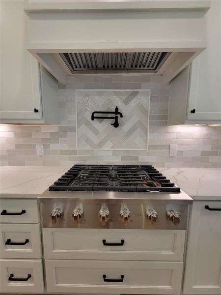 This modern kitchen features a sleek gas stove with six burners, complemented by a stylish tile backsplash and a convenient pot filler. The light cabinetry and countertops provide a clean, elegant look. This modern kitchen features a sleek gas stove with six burners, complemented by a stylish tile backsplash and a convenient pot filler. The light cabinetry and countertops provide a clean, elegant look.