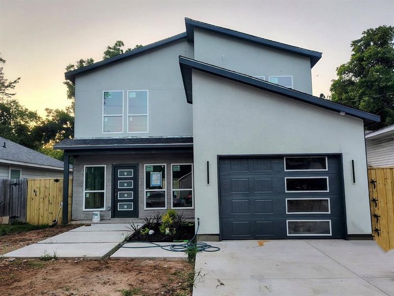 Modern home with driveway, stucco siding, and a garage Modern home with driveway, stucco siding, and a garage