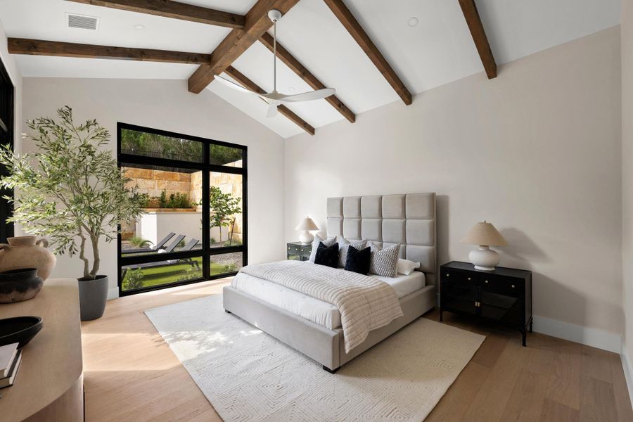 Sequestered in its own wing, the primary retreat features a vaulted ceiling with exposed wood beams and floor-to-ceiling glass oriented toward the backyard