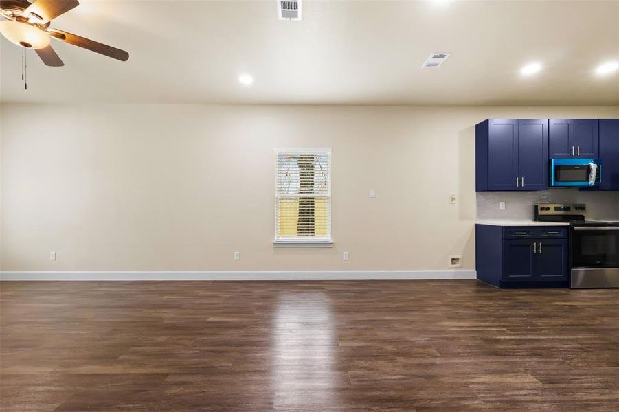 Kitchen with tasteful backsplash, dark wood-type flooring, ceiling fan, and stainless steel range with electric stovetop