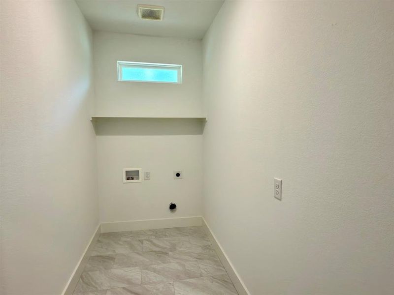 Dedicated utility space featuring tile flooring, a high transom window, and a built-in shelf