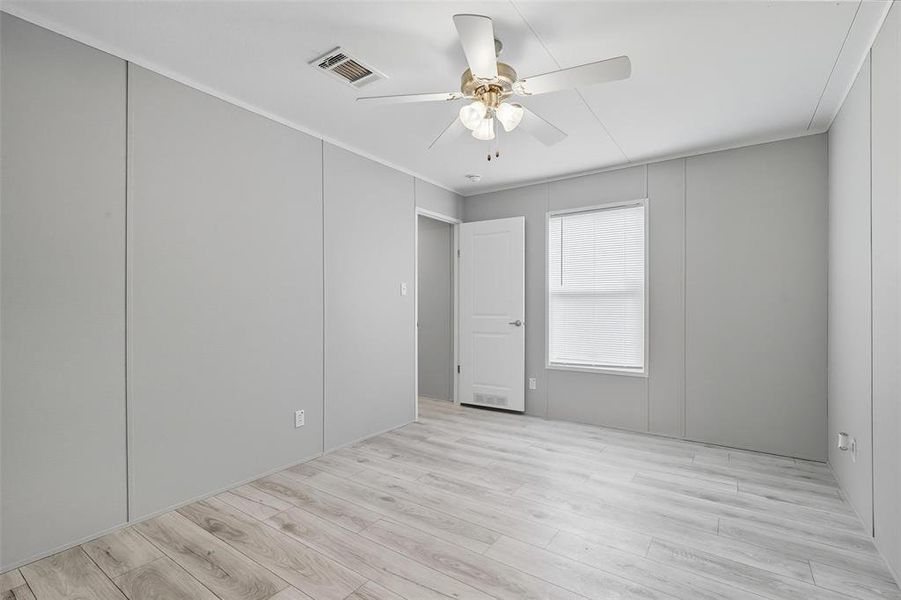 Unfurnished room with light wood-style floors, ceiling fan, and a decorative wall Unfurnished room with light wood-style floors, ceiling fan, and a decorative wall