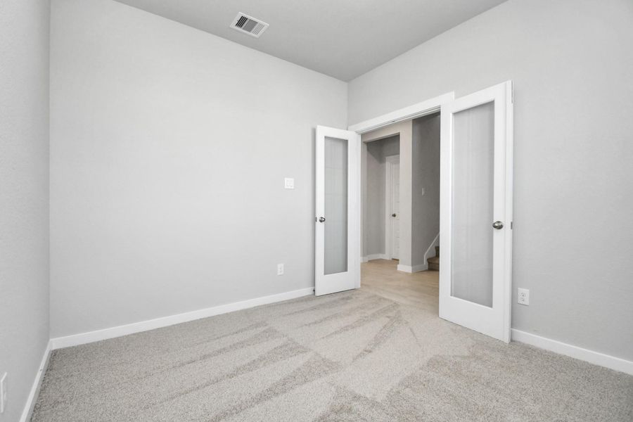 At the forefront, a refined home office beckons productivity and focus. Luxurious details like tile flooring, custom paint, expansive windows with privacy blinds, and French doors create an inspiring workspace. Sample photo of completed home with similar floor plan. Actual colors and selections may vary.