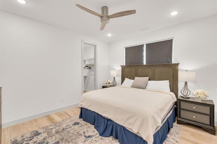 Bedroom featuring a walk in closet, ceiling fan, light hardwood / wood-style flooring, and a closet