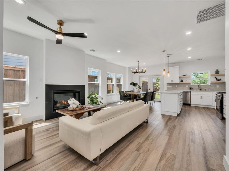 Living area with a glass covered fireplace, recessed lighting, a chandelier, light wood-style flooring, and a ceiling fan Living area with a glass covered fireplace, recessed lighting, a chandelier, light wood-style flooring, and a ceiling fan