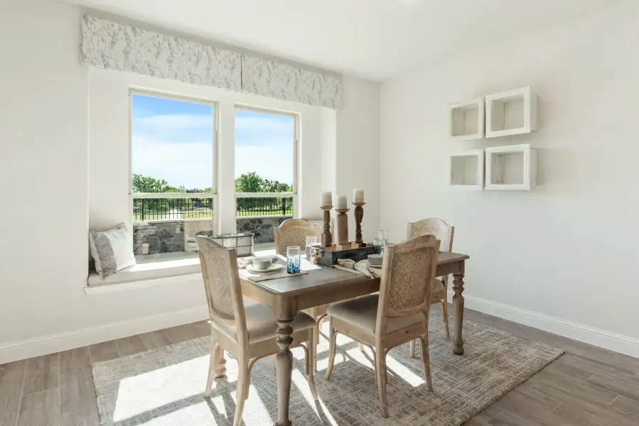 Dining room with wood table, four chairs, window seat, and large windows overlooking a patio