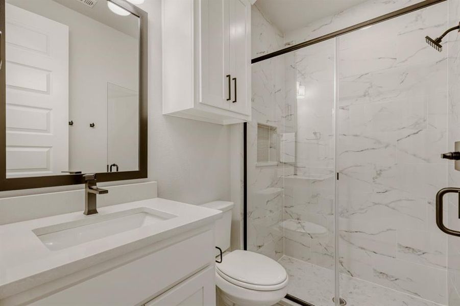 Bathroom with a marble finish shower and vanity
