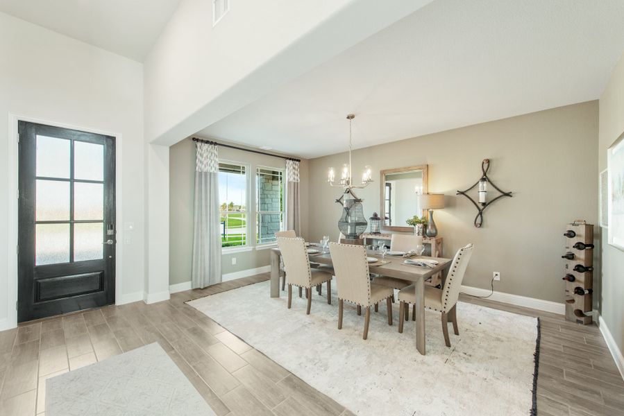Dining room with six-chair table, chandelier, and black front door visible near entryway
