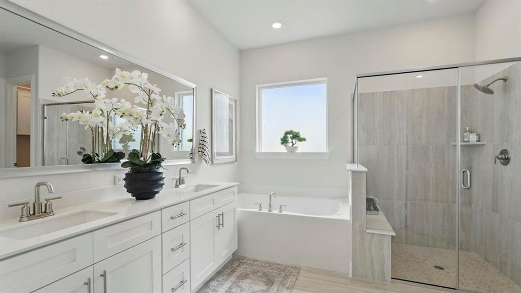 Bathroom featuring a shower stall, double vanity, a bath, and recessed lighting