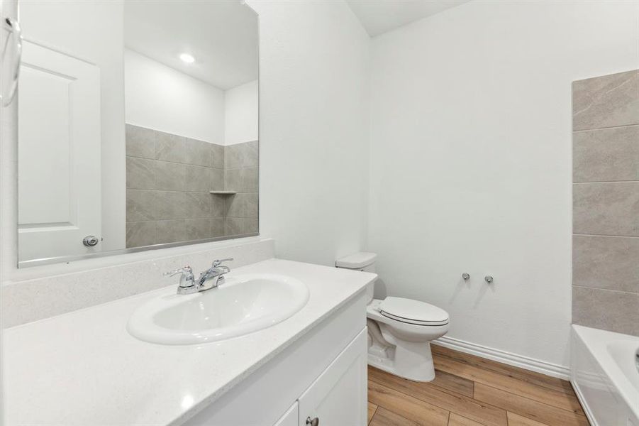 Full bathroom featuring tiled shower / bath combo, vanity, toilet, and wood-type flooring