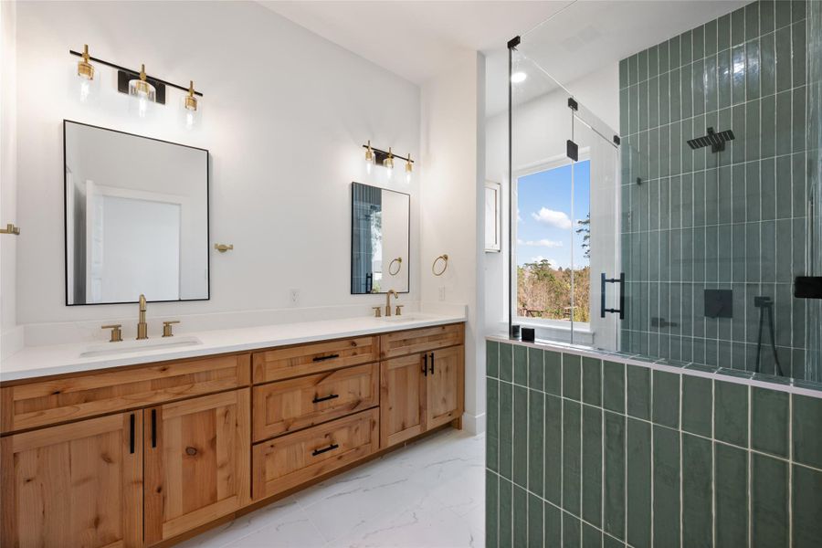 Bathroom with a shower stall, light marble finish flooring, double vanity, and recessed lighting