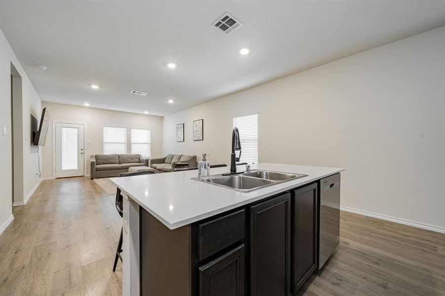 Kitchen featuring light wood finished floors, recessed lighting, an island with sink, open floor plan, and stainless steel dishwasher Kitchen featuring light wood finished floors, recessed lighting, an island with sink, open floor plan, and stainless steel dishwasher