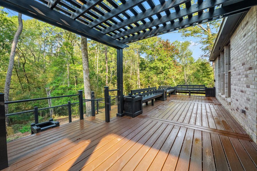 A spacious Trex deck with a pergola and built-in benches, offering a serene view of lush, green trees. Perfect for outdoor relaxation and entertaining. A spacious Trex deck with a pergola and built-in benches, offering a serene view of lush, green trees. Perfect for outdoor relaxation and entertaining.