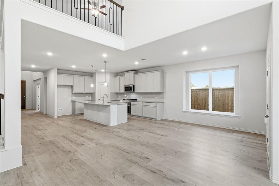 Kitchen featuring a center island with sink, light wood-style flooring, recessed lighting, open floor plan, and stainless steel appliances