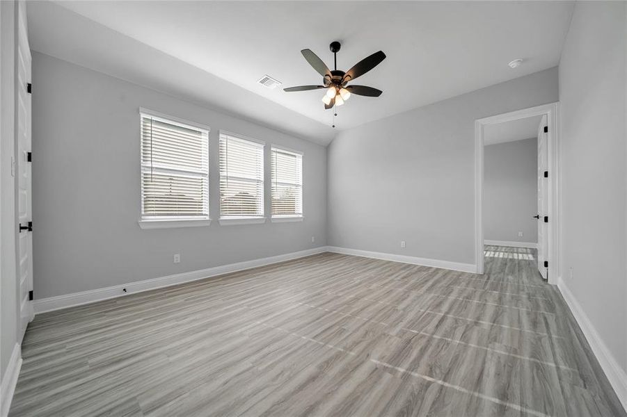 Unfurnished room with light wood-style flooring, lofted ceiling, and a ceiling fan Unfurnished room with light wood-style flooring, lofted ceiling, and a ceiling fan