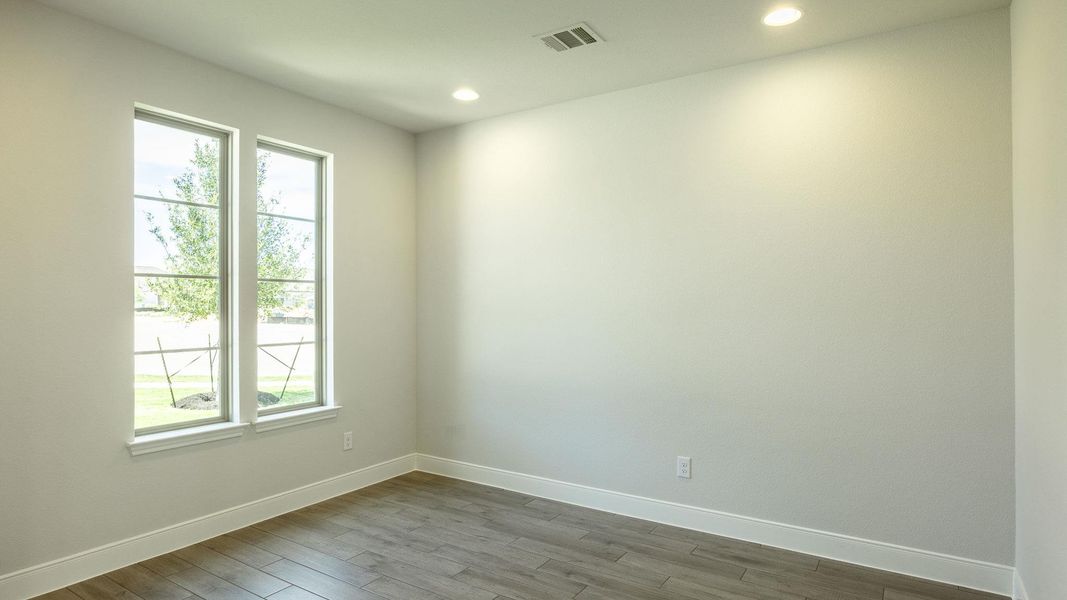 Empty room featuring healthy amount of natural light, baseboards, dark wood-style floors, and recessed lighting Empty room featuring healthy amount of natural light, baseboards, dark wood-style floors, and recessed lighting