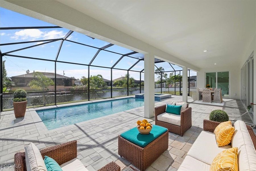 View of swimming pool featuring a sunroom, a patio, a water view, a pool with connected hot tub, and an outdoor hangout area