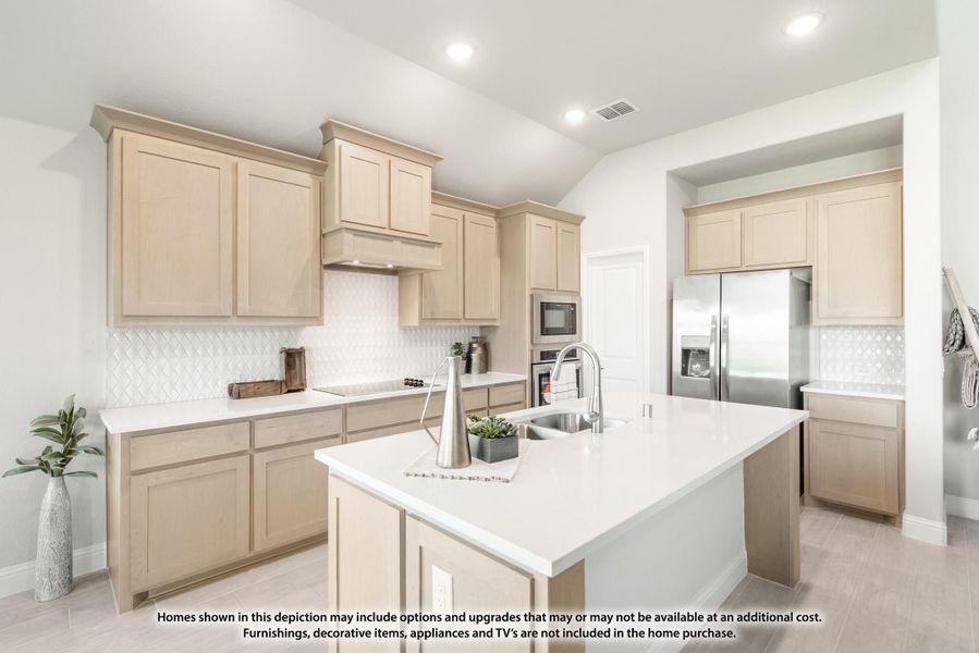 Kitchen with light wood cabinets, white island with sink, and stainless steel appliances