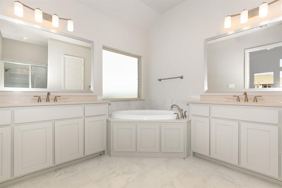 Full bath with a shower stall, two vanities, a garden tub, and light marble finish floors