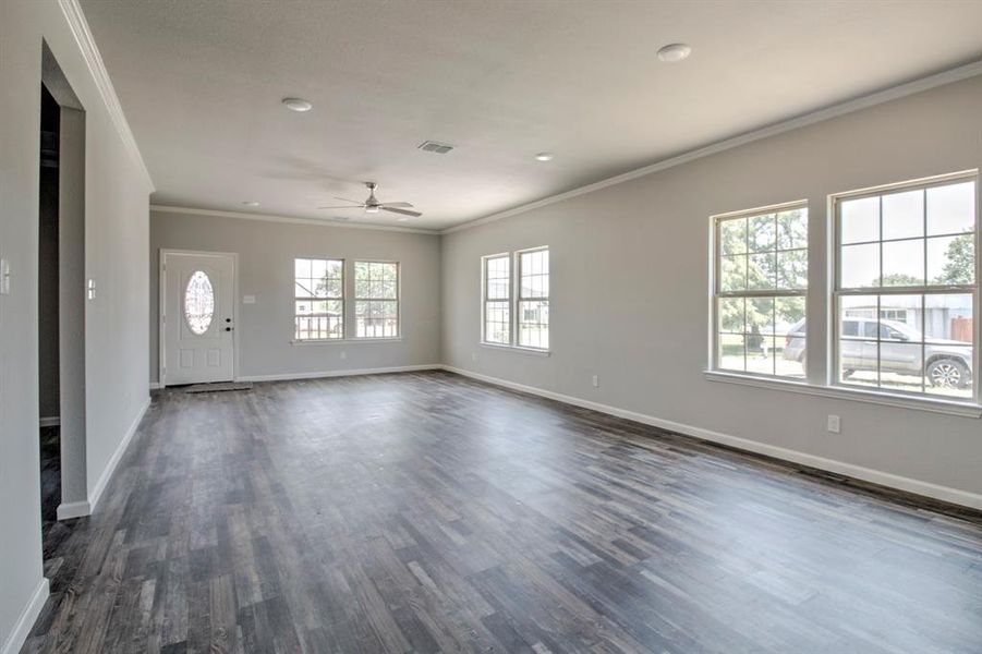 Empty room with crown molding, a wealth of natural light, and dark hardwood / wood-style flooring