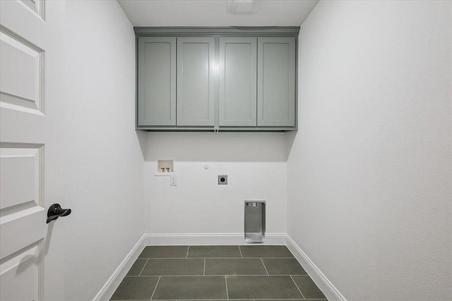 Laundry area with electric dryer hookup, cabinet space, hookup for a washing machine, dark tile patterned floors, and gas dryer hookup Laundry area with electric dryer hookup, cabinet space, hookup for a washing machine, dark tile patterned floors, and gas dryer hookup