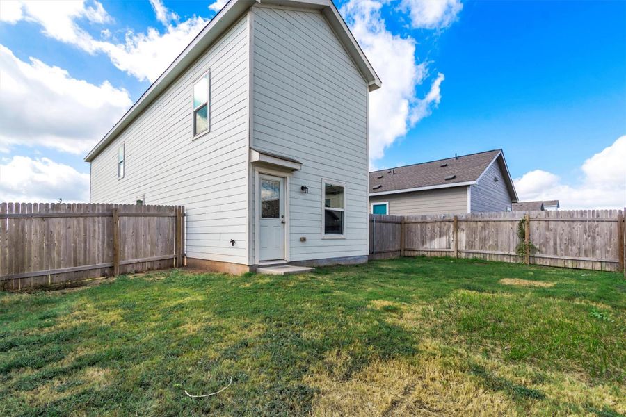 A spacious grassy yard sits enclosed by sturdy wood fencing behind the home. A spacious grassy yard sits enclosed by sturdy wood fencing behind the home.