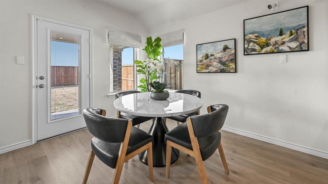 Dining space with wood finished floors and lofted ceiling